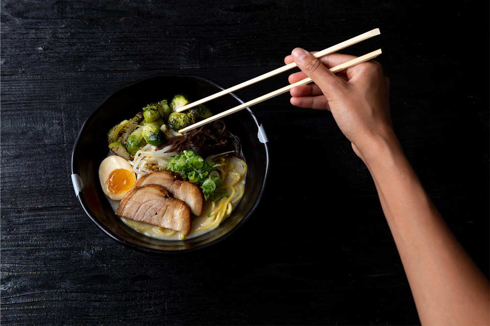 close up of person eating ramen with chopsticks